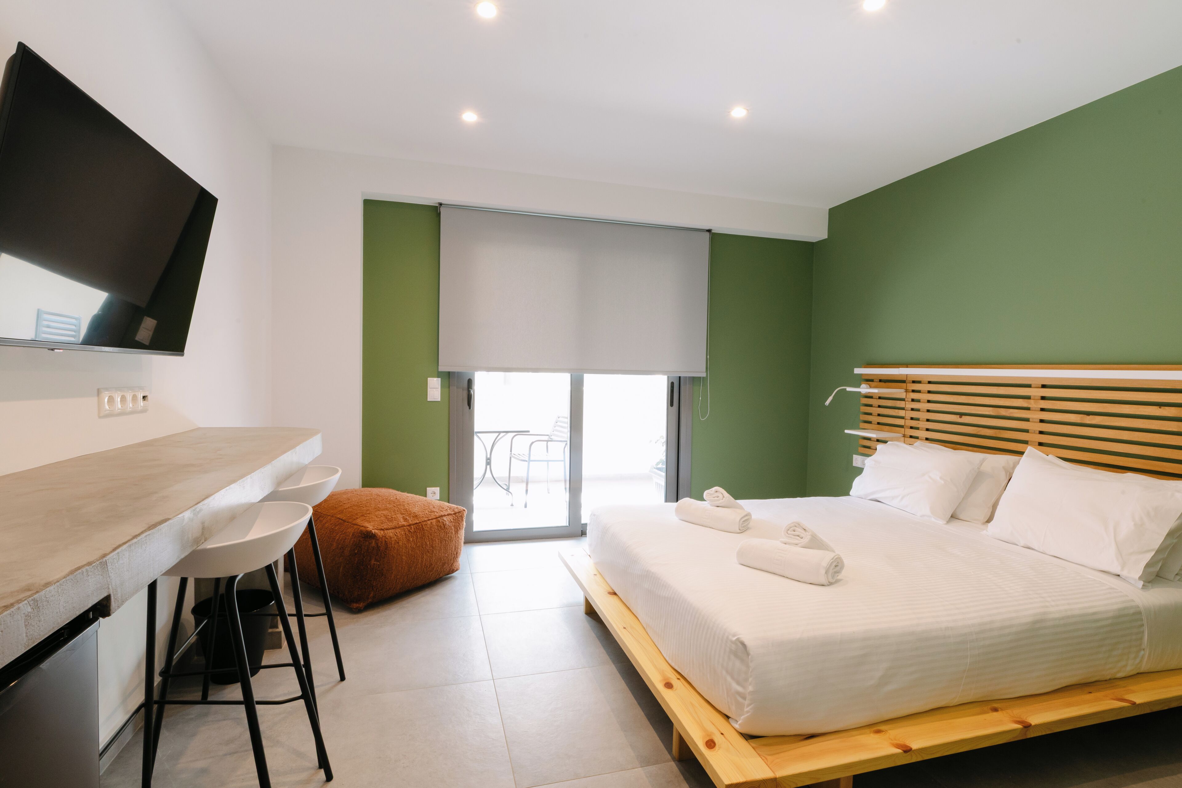 A modern hotel room with a bed, a desk, and a TV.