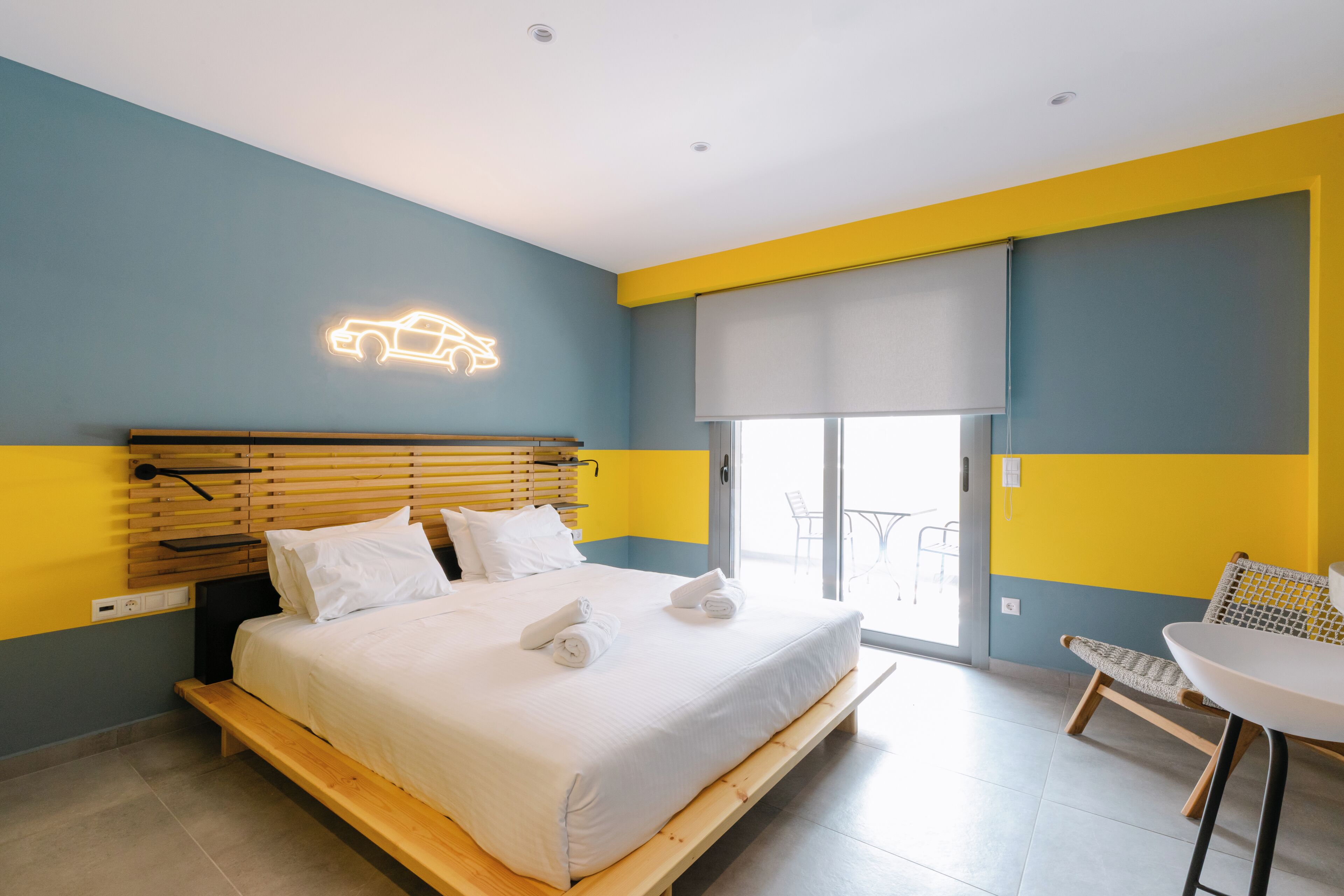 A modern hotel room with a bed, a seating area, and a large window.