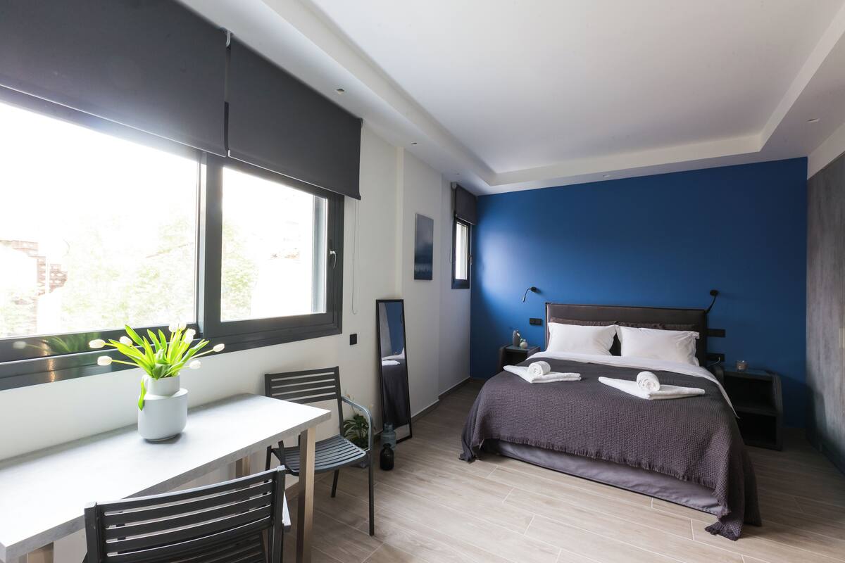 A modern bedroom with a bed, bedside tables, a desk, and a chair.