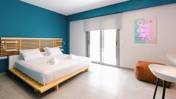 Ein modernes Schlafzimmer mit einem hölzernen Bett, einem weißen Nachttisch und einer leuchtend blauen Wand.