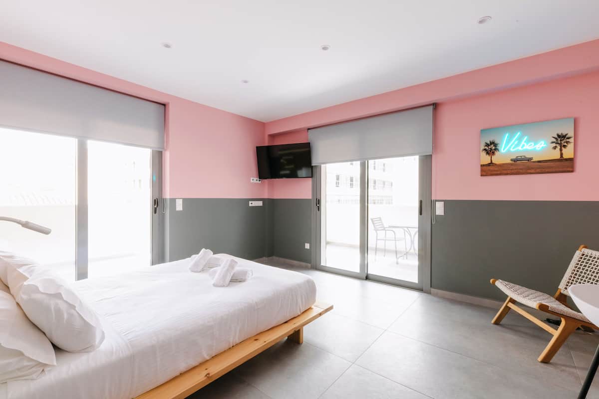 A modern bedroom with a bed, a chair, and a TV on the wall.
