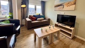 A modern living room with a sofa, a coffee table, a TV, and a painting on the wall.