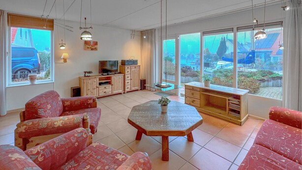 Ein geräumiges Wohnzimmer mit großem Fenster, Fernseher und Esstisch.