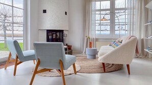 A modern living room with two armchairs, a fireplace, and large windows offering a view of the outdoors.