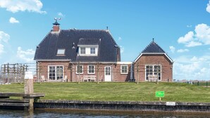 A brick house with a large front lawn and a canal in front.