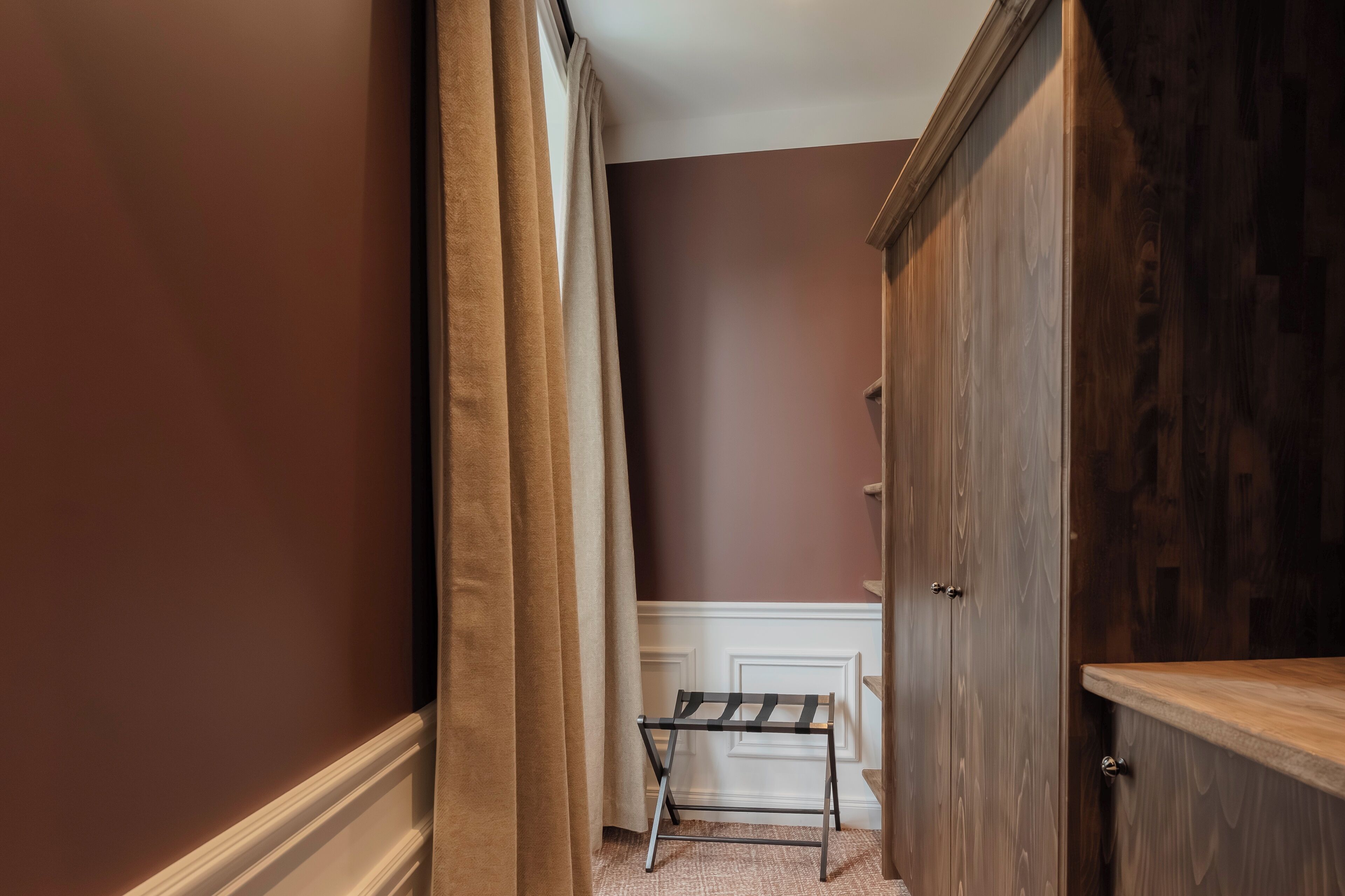 A hallway with a bench, wooden wardrobe, and a door.