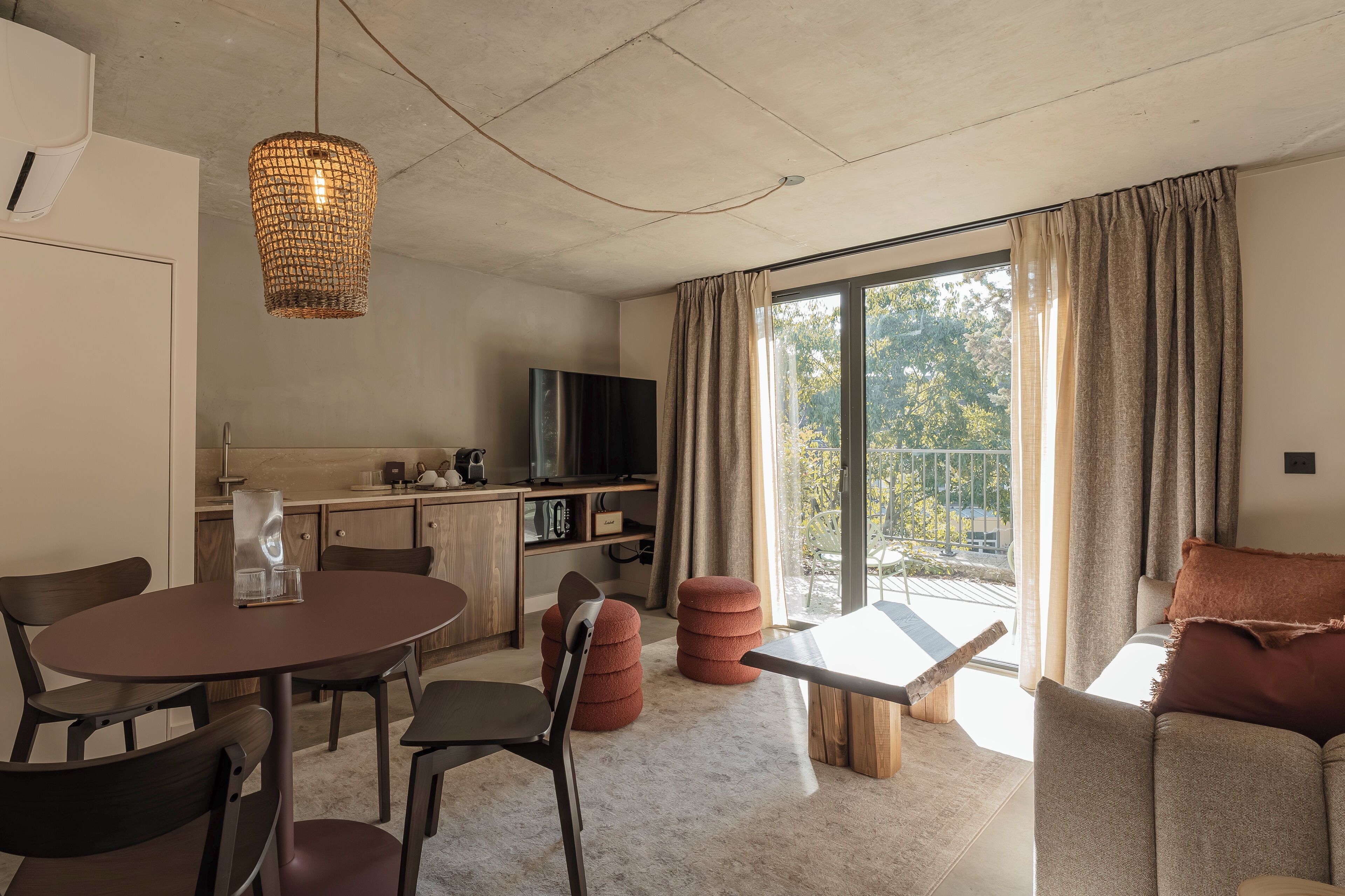 A modern living room with a dining area, a kitchen, and a balcony with curtains.