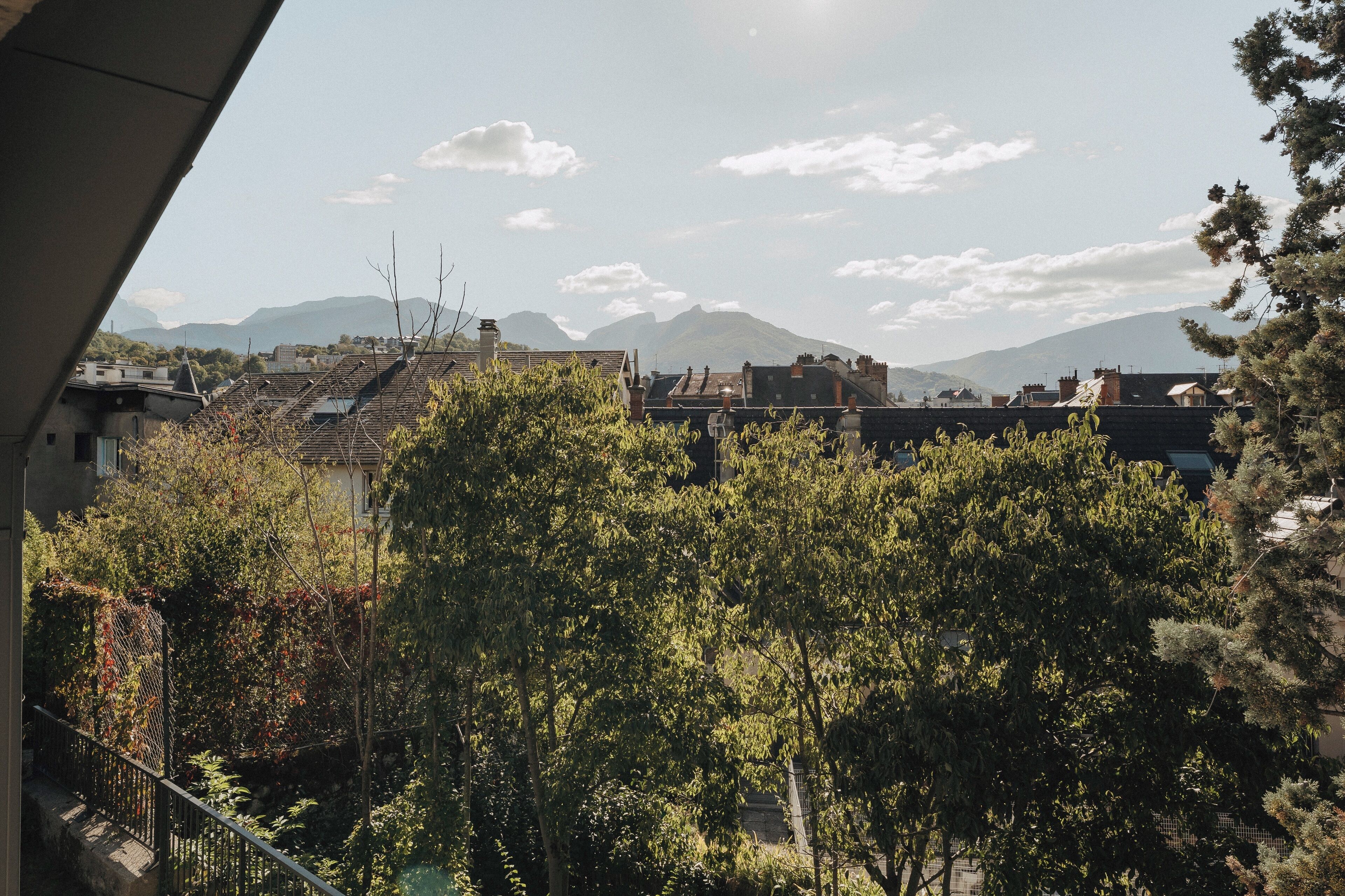 A residential area with houses, trees, and mountains in the background.