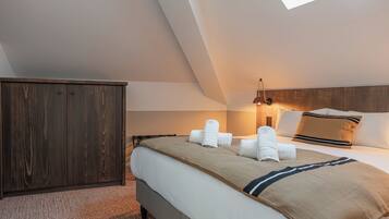 A modern hotel room with a large bed, a wardrobe, and a skylight.