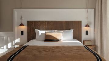 Una cama bien hecha con una manta marrón y almohadas, un cabecero de madera y dos lámparas de noche.