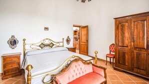 A bedroom with a bed, wooden wardrobe, a chair, and a dresser.