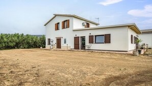 A two-story house with a dirt yard, wooden shutters, and a satellite dish.