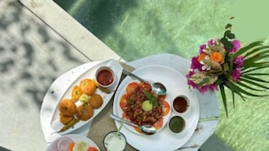 A table with various dishes including tacos, a salad, and a plate with a flower arrangement. - Tiger Safari Lodge (Ashta)