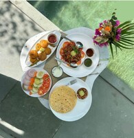 A table with various dishes including tacos, a salad, and a plate with a flower arrangement.