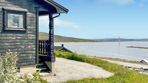 Una cabaña de madera con un porche que da a un lago.