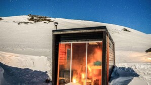 Una montaña nevada con una pequeña estructura de cabaña iluminada.