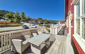 Ein Balkon mit Korbmöbeln und Blick auf Gleise und geparkte Autos.