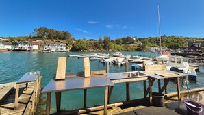 A marina with docked boats, wooden docks, and houses in the background.
