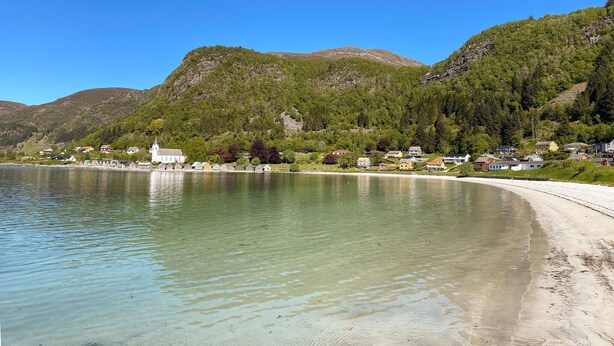 Une ville côtière avec une église, des maisons et un lac aux eaux limpides.