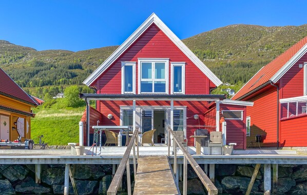 A red house with a wooden deck and a staircase leading to the entrance. - Nice home in Gursken with WiFi (Gursken)