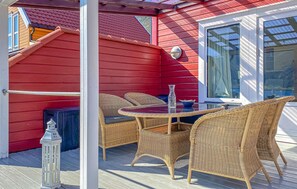 A red exterior wall, a glass door, wicker furniture, and a lantern on a deck. - Nice home in Gursken with WiFi (Gursken)