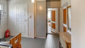 A hallway with white paneled walls, a wooden bench, and a fire extinguisher.