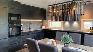 Una cucina moderna con mobili scuri, forno integrato, lavello e zona pranzo con tavolo e sedie.