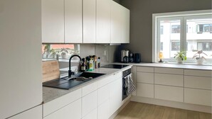 A modern kitchen with white cabinets, a black countertop, and a window with a view of buildings. - 4 bedroom beautiful apartment in Oslo (Oslo)