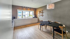 A modern kitchen with a large window, wooden flooring, and a dining area with a round table and chairs. - 4 bedroom beautiful apartment in Oslo (Oslo)