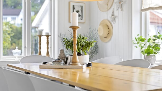 A dining area with a wooden table, white chairs, a potted plant, and a candle holder. - Nice home in Tvedestrand with WiFi (Tvedestrand)