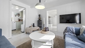 A modern living room with a white sofa, a round white table, and a flat-screen TV mounted on the wall. - Nice home in Tvedestrand with WiFi (Tvedestrand)