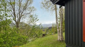 A wooden cabin with a view of a grassy area and trees.
