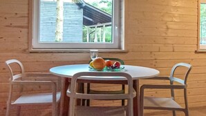 Een ronde tafel met een glazen blad, omringd door vier witte stoelen. Op de tafel staat een bord met fruit en een glas water.