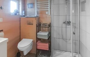 A bathroom with a toilet, a shower, and a shelf with folded towels. - Pet friendly home in Karsin with sauna (Karsin)