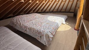 A cozy attic bedroom with wooden slats, two beds with floral bedding, and a view of trees through a skylight. - Ecolodge located in the heart of nature, between land and sea. (Arzano)