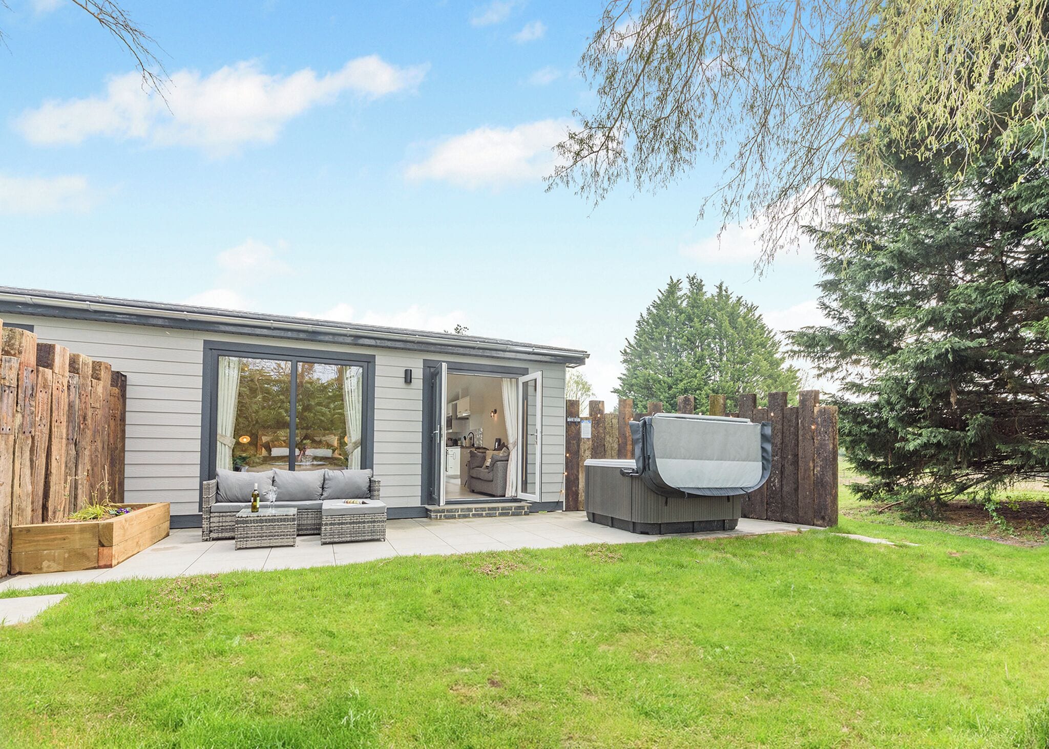 Una casa moderna con patio, mobiliario exterior y televisor.