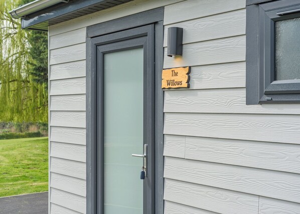 A house with a gray exterior, a glass door, and a sign reading 'The Willows.'