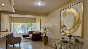 A spacious living area with a sofa, a coffee table, and a large abstract painting on the wall. - Hermoso espacio a pie de playa y alberca By Gps (Mazatlan)