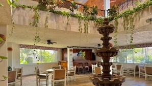 A spacious indoor area with a central fountain, wooden flooring, and a seating area with chairs and tables.