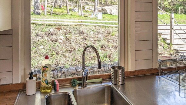 A kitchen with a stainless steel sink, a faucet, and a window overlooking a rocky outdoor area. - Gorgeous home in Hovås with WiFi (Hovås)