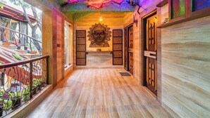 A corridor with wooden flooring, a ceiling mural, and a large Buddha statue.