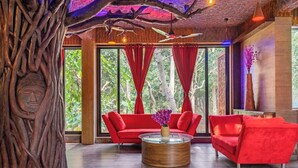 A modern interior with a red sofa, a round wooden coffee table, and a large tree sculpture.