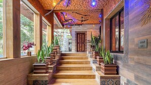 A wooden staircase with potted plants, leading to a door with a decorative design.