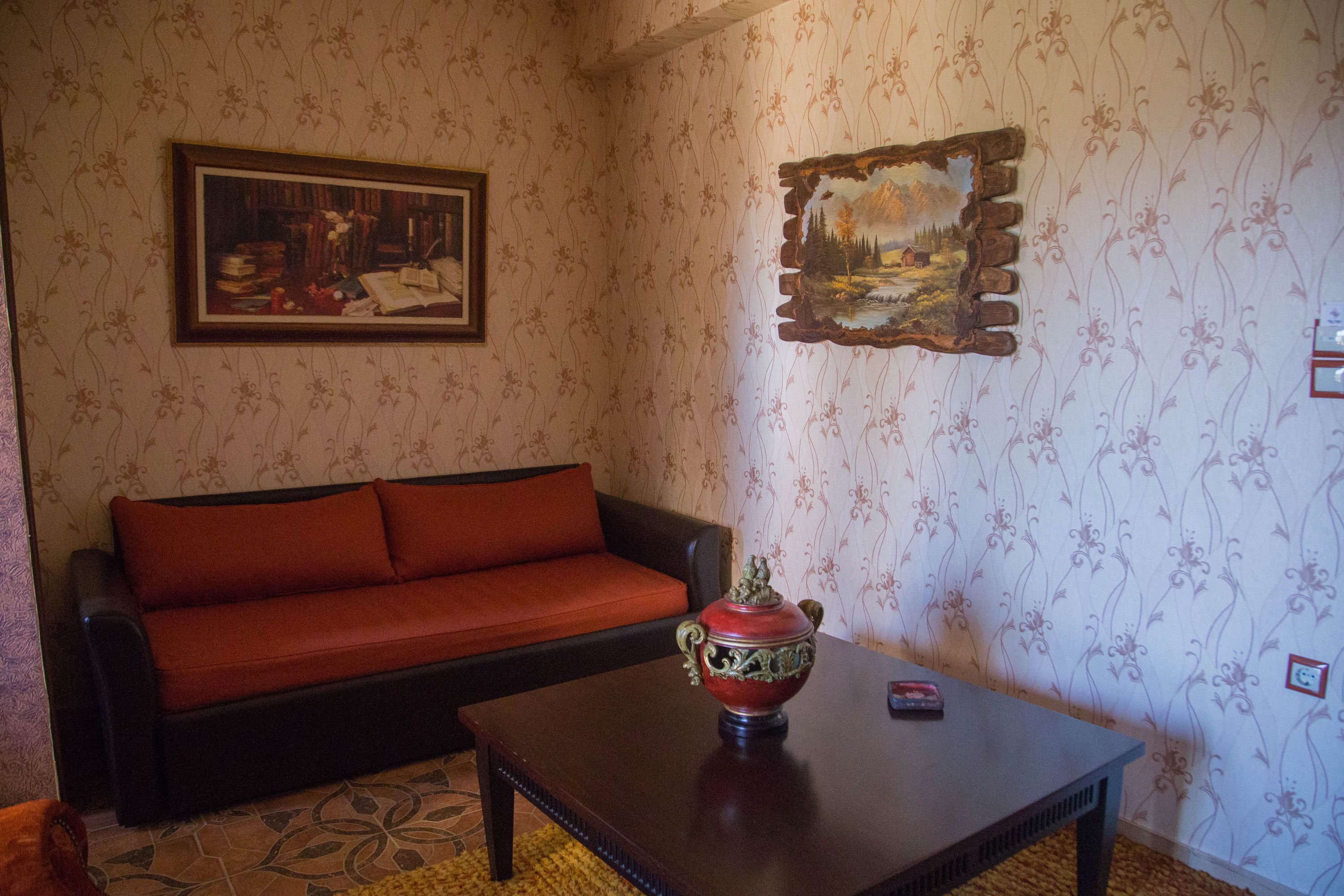 A room with a sofa, a table, and two paintings on the wall.