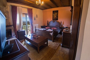 A bedroom with a bed, a wooden desk, a television, and a view of the outdoors. - Silva Suites - Kryoneri, Lake Plastira (Lake Plastiras)