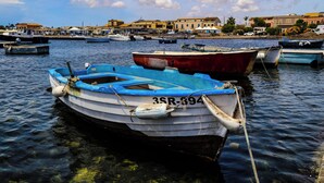 A marina with several boats docked, a clear sky, and buildings in the background.