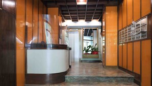 A hotel reception area with a curved reception desk, a staircase leading to an upper floor, and a door leading to a room with a view of the outdoors. - Mazzini Suites Palermo (Palermo)