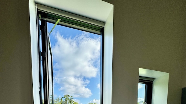 A bedroom with a large bed, a small window, and a view of a green landscape. - Ubberup Konferencegaard (Kalundborg)