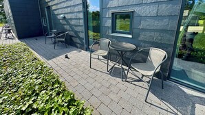 A modern building exterior with a patio area featuring outdoor furniture and a glass door. - Ubberup Konferencegaard (Kalundborg)