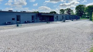 A building with a gravel driveway and a row of rooms with large windows. - Ubberup Konferencegaard (Kalundborg)